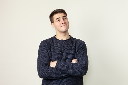 Studio portrait of 19 year old man with short brown hair in blue sweater on white background