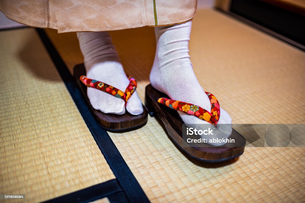 Traditional Japanese ryokan house home with tatami mat floor and closeup of woman in kimono and geta shoes tabi socks walking inside Geta Sandal Stock Photo