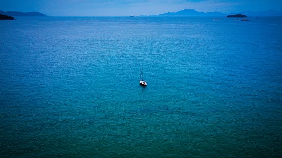 A sailboat navigates in the limpid waters of the Angra dos Reis bay, Rio de Janeiro - Brazil