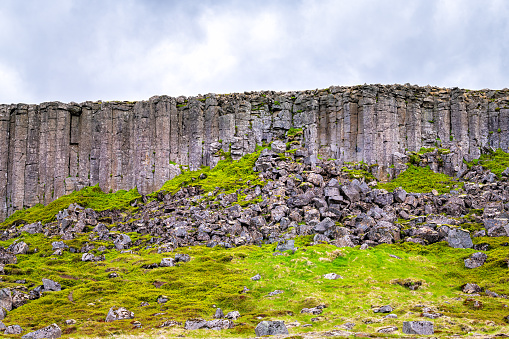 Gerduberg Basalt Columns view of landscape in Snaefellsnes Iceland with green grass on summer day and clouds in sky