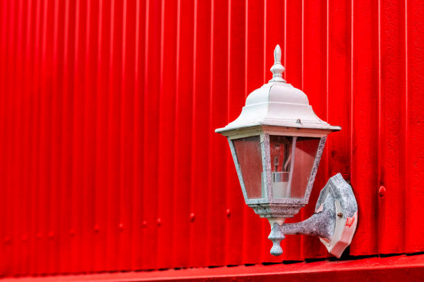 Corrugated ribbed red painted peeling paint wall of abstract architecture building with electric bulb lamp lantern outside on house in Reykjavik, Iceland