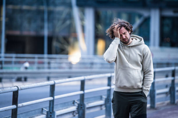Young man having a headache. Sporty young man having a headache, problems while walking in the city. athlete fails stock pictures, royalty-free photos & images