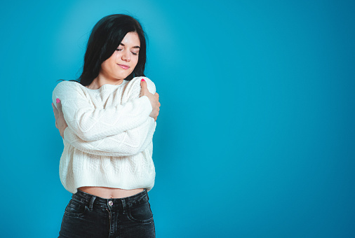 Young woman wearing casual sweater Hugging herself, she is happy and positive and confident. Self love and self care stock photo