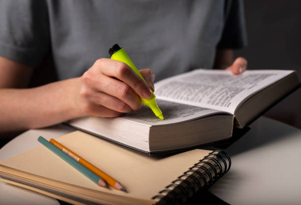 istock Female student hands holding yellow highlighter and reading book or textbook, making notes, underlines, prepare for exam at table at night. Education concept 1311870284