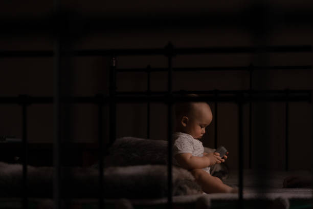 Baby gnaws at the edge crib during teething itching. Funny lop-eared child scratching his teeth on the rail bed, age six months