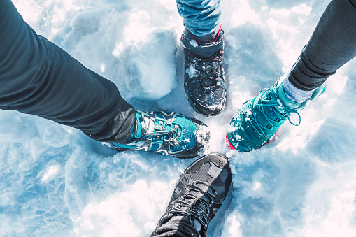 AERIAL VIEW OF FOUR FEET TOGETHER WITH HIKING BOOTS IN THE SNOW