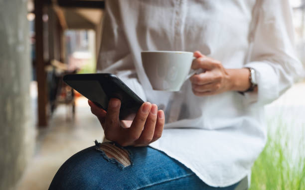 istock a woman holding and using mobile phone while drinking coffee 1311888602