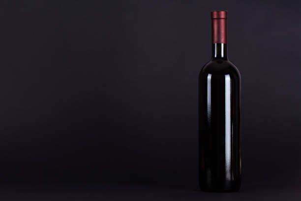 istock Sealed bottle of red wine on a lilac background.With space for text. Wine tasting and drinking culture concept. 1311891120