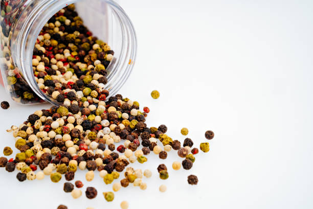 a mixture of peppers is scattered from a jar on a white background. traditional spices for cooking.