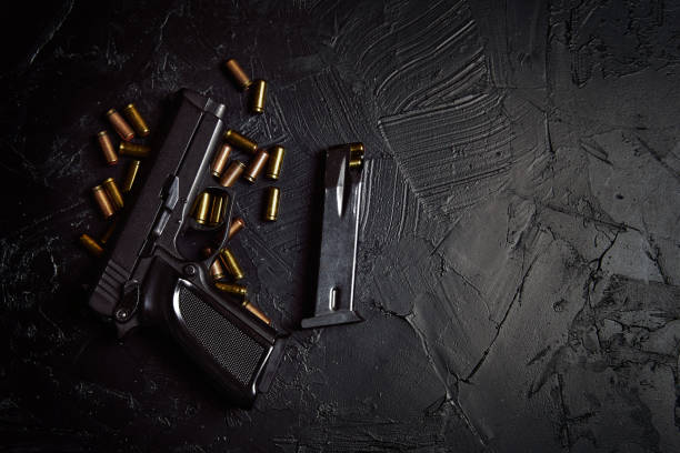 istock Pistol with cartridges on black concrete table. 1311896900