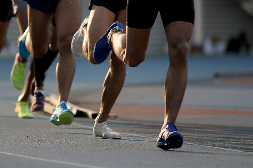 Focus scene on athletes running marathon in track and field stadium.