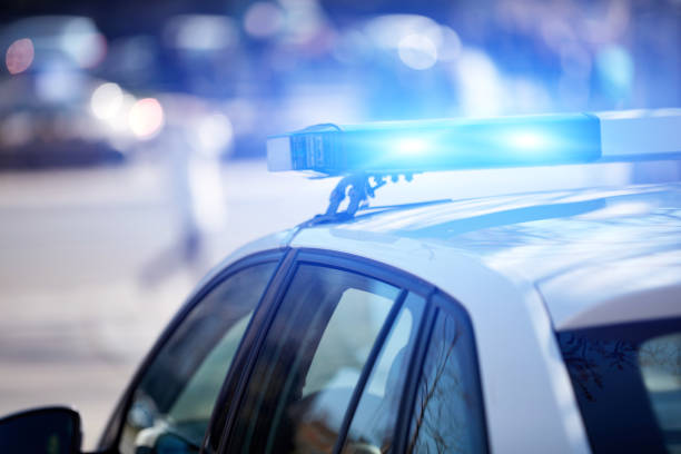 police car with blue lights on the crime scene in traffic urban environment. - policia imagens e fotografias de stock