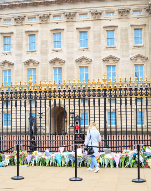 Floral Tributes Buckingham Palace, London.  A member of the public laying a floral tribute to Prince Philip with the Queens Guard standing Sentry, London, UK, April 2021 prince phillip stock pictures, royalty-free photos & images