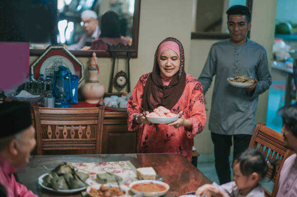 ramadã hari raya avó malaia, filho e nora servindo comida para a família na sala de jantar - great granddaughter - fotografias e filmes do acervo