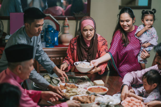 ramadan hari raya malay babcia, syn i syn w prawo obsługujących jedzenie dla rodziny w jadalni - muslim festival zdjęcia i obrazy z banku zdjęć