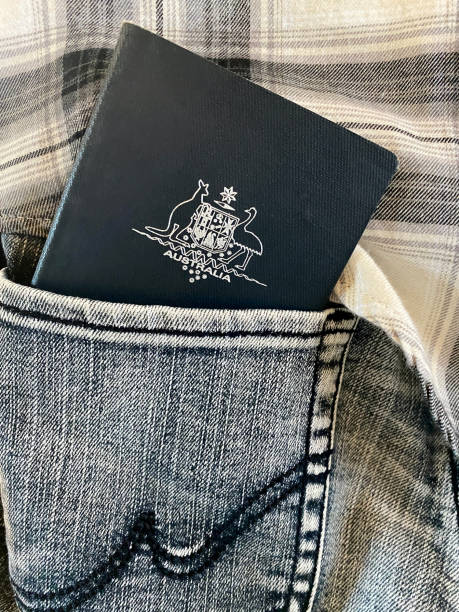 Australian Passport in Jeans Pocket Closeup photo of an Australian passport just inside the back pocket of a woman's grey denim jeans. Part of a black and cream flannelette shirt can be seen behind the passport. jeans denim passport pocket stock pictures, royalty-free photos & images
