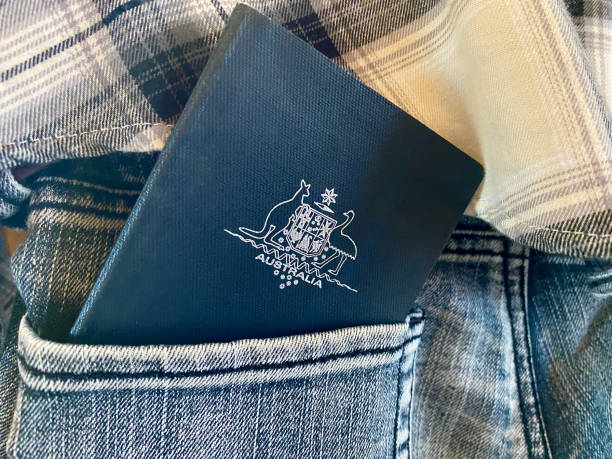 Australian Passport in the Pocket of Blue Jeans Horizontal closeup of an Australian passport just inside the back pocket of a woman's blue denim jeans, in front of a checked flannelette shirt worn above the jeans jeans denim passport pocket stock pictures, royalty-free photos & images