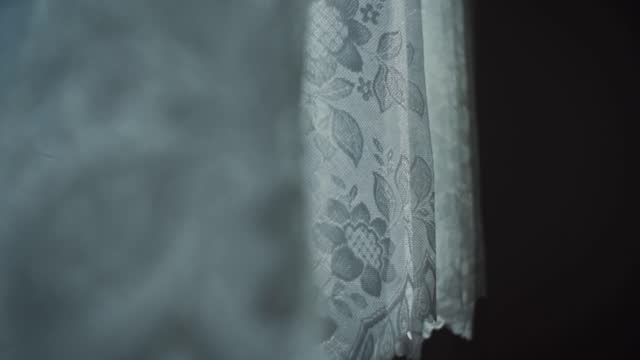 Whiten lace curtain waiving on the breeze