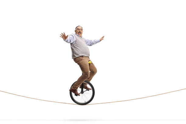 full length profile shot of an excited mature man riding a mono-cycle on a rope - unicycle unicycling cycling wheel imagens e fotografias de stock