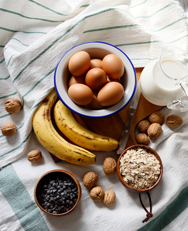 Istanbul, Turkey-March 10, 2021: A plate of eggs, bananas, milk in a glass jug, walnuts, oats, chocolates on a wooden cutting board. Full Frame, Still life, Flat lay. Shot with Canon EOS R5.