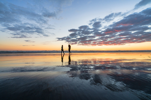 Two woman friends enjoying nature's beauty after full day surfing.