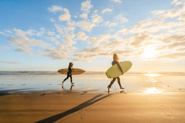 surfando na praia na hora do pôr do sol. - murawai beach - fotografias e filmes do acervo