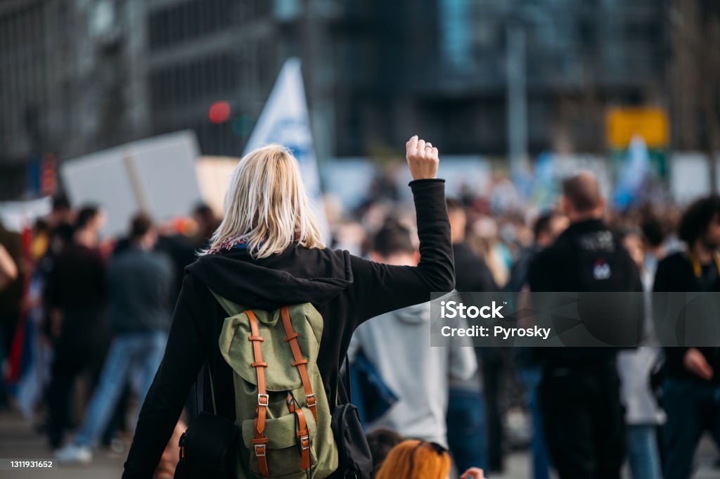 Rear view of a female protester raising her fist up Young woman with a raised fist protesting in the street in front of the government building.
2021 Protest Stock Photo