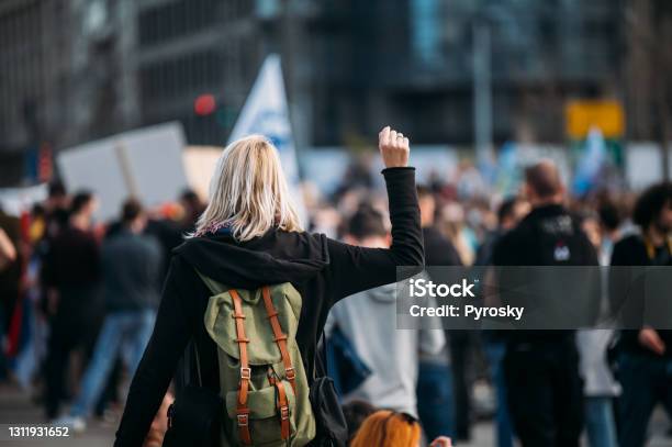 Rear View Of A Female Protester Raising Her Fist Up Stock Photo - Download Image Now