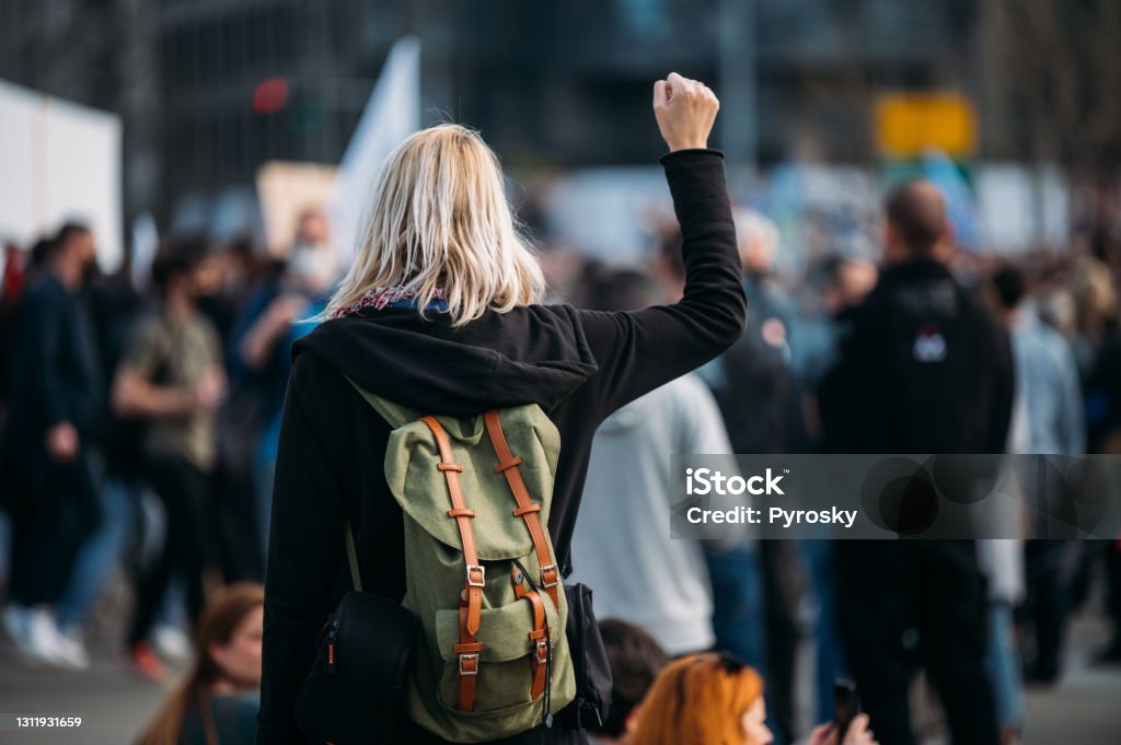 Rear view of a female protester raising her fist up Young woman with a raised fist protesting in the street in front of the government building.
2021 Women Stock Photo