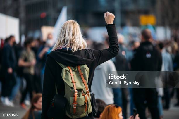 Rear View Of A Female Protester Raising Her Fist Up Stock Photo - Download Image Now