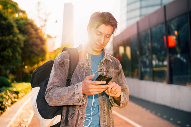 istock Young man using smart phone under sunlight on the streets. 1311931761