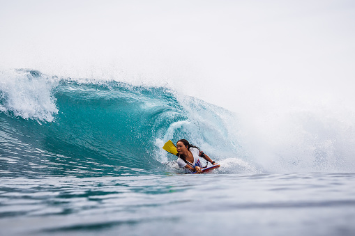 December 09, 2020. Bali, Indonesia. Bodyboarder girl ride on barrel wave. Professional surfing in ocean
