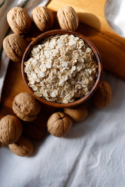 Oatmeal on wooden plate on tablecloth and wooden cutting board and walnuts