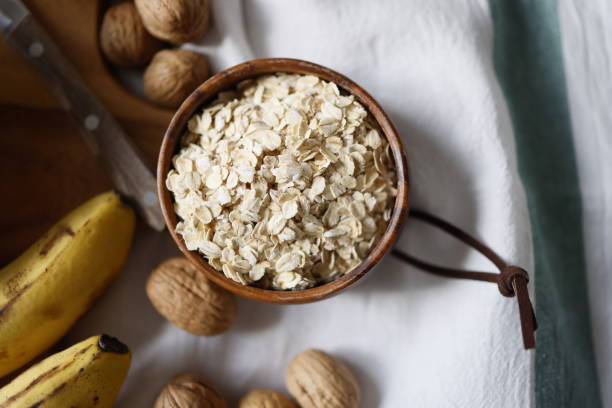 Oatmeal on wooden plate on tablecloth and wooden cutting board and walnuts, Flat lay, close-up