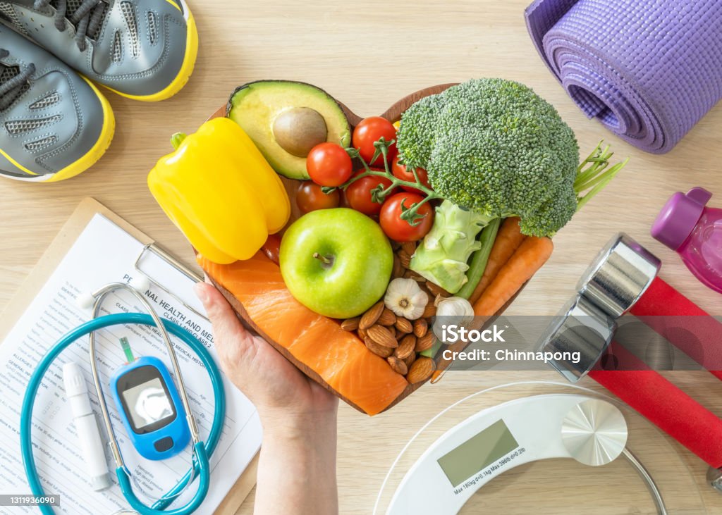 Healthy lifestyle on ketogenic diet, eating clean keto food good health dietary in heart dish with aerobic body exercise, gym workout training class , weight scale and sports shoes in fitness center Healthy Lifestyle Stock Photo