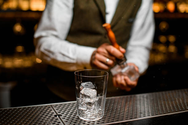 istock glass with ice cubes on bar. Bartender is cracking ice in the background 1311937072