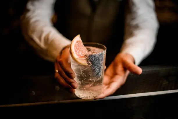 Photo of transparent glass with freshness drink in hands of male bartender