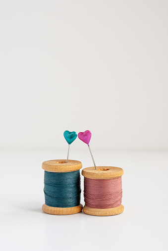 Pair of sewing needles with hearts and two vintage wooden spools of thread