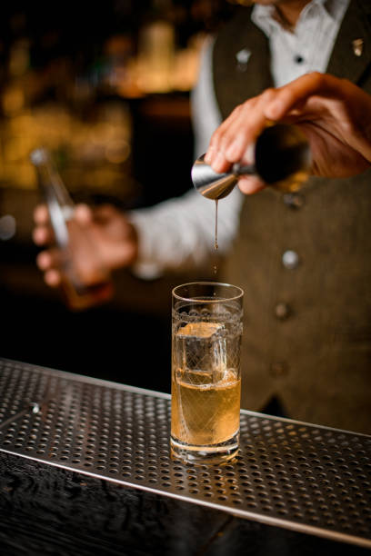 istock bartender holds steel jigger and gently pours beverage to glass with ice 1311939688