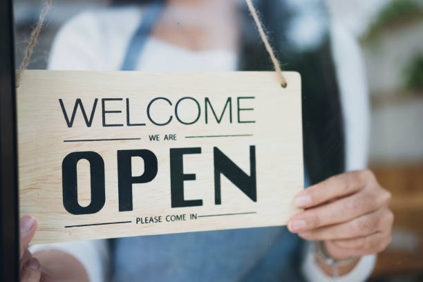 Close up of womanÂÂ hands holding sign now we are open support local business. Small business owner smiling while turning the sign for the reopening of the place after the quarantine due to covid-19. Close up of womanÂÂ hands holding sign now we are open support local business. restaurant labor union stock pictures, royalty-free photos & images