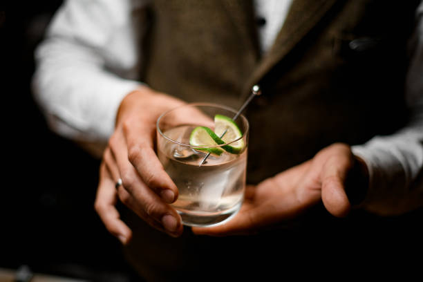 Great close-up view of glass with freshness drink in hands of male bartender Great close-up view of transparent glass with freshness drink decorated by citrus in hands of male bartender. Blurred background gin tonic stock pictures, royalty-free photos & images