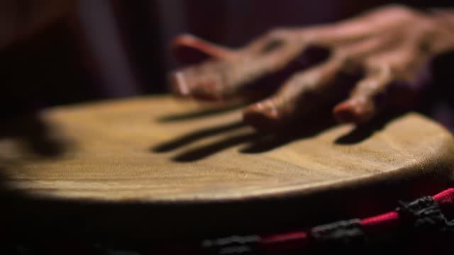 Black musician plays with hands on drum. On the African drum man beat the rhythm with hands, close-up