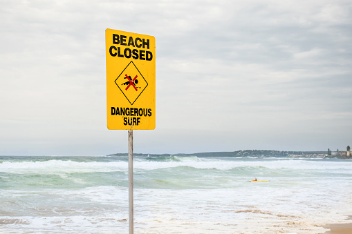 Beach closed sign for swimmers at the beach in Australia. Dangerous surf and high tide