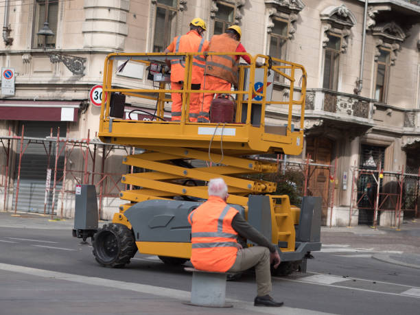 two workers with orange overalls inside a lift rack working in a city street and elderly man sitting watching them - rack railway imagens e fotografias de stock