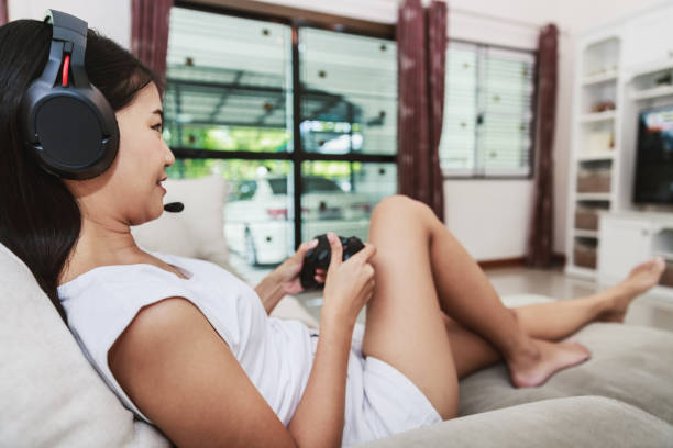 istock Asian woman play video game console at home 1311947701