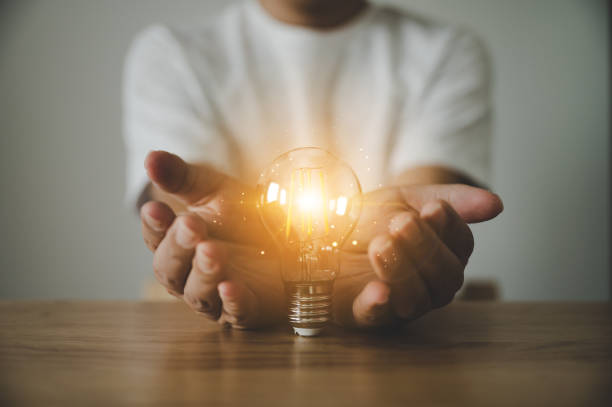 istock Hand holding light bulb on wood table. Concept of inspiration creative idea thinking and future technology innovation 1311947711