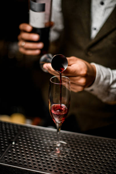 istock transparent glass is on bar and bartender pours drink from steel jigger into it 1311947917