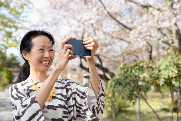 istock Japanese woman enjoying cherry bloosms 1311949617