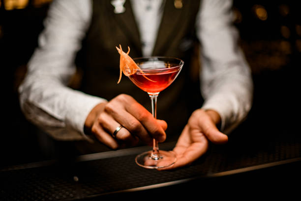 bicchiere di vino con cocktail alcolico luminoso alla moda in mani di barista maschio - servizio di lusso foto e immagini stock