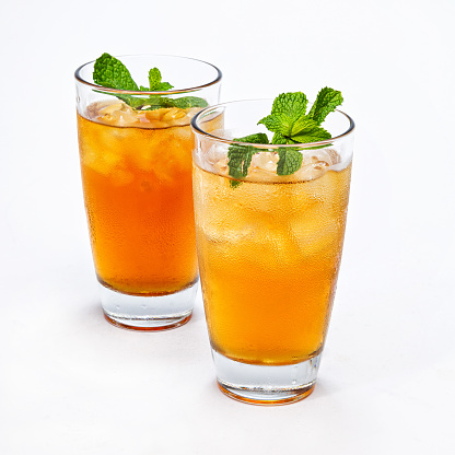 Two glasses of ice tea with mint on a white background.